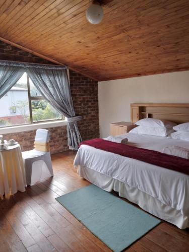 a bedroom with a large bed and a large window at Hamba Kancane Ma-Africa Guest House in Graskop