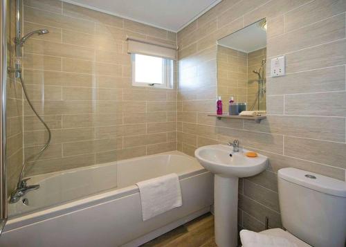 a bathroom with a tub and a sink and a toilet at Jamies Cragg Holiday Park in Welburn