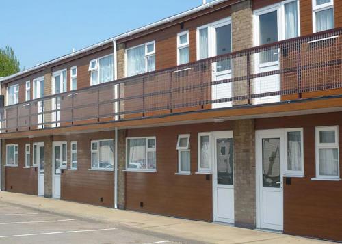 a brick building with white doors and a balcony at North Shore Holiday Park in Winthorpe