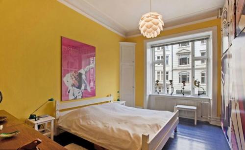 een gele kamer met een bed en een raam bij Copenhagen Apartment with excellent location in Kopenhagen