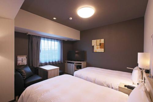 舞鶴市にあるHotel Route Inn Kyoto Maizuru -Nishi Maizuru Ekimae-のベッド2台、椅子、テレビが備わるホテルルームです。