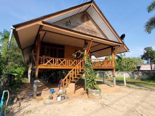 a house with a large porch and a staircase in front at Artist Homestay in Ko Yao Noi