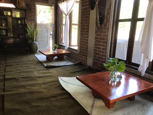 a living room with two tables and windows at Les Cantik Homestay in Tejakula