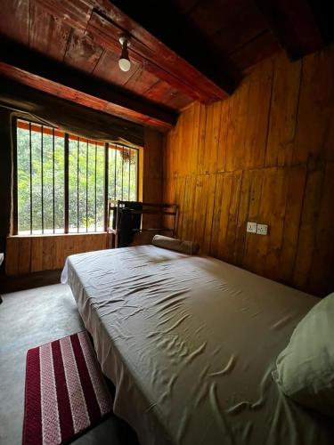 a bedroom with a large bed in a wooden room at Riverston Du Eco Cottage in Rattota