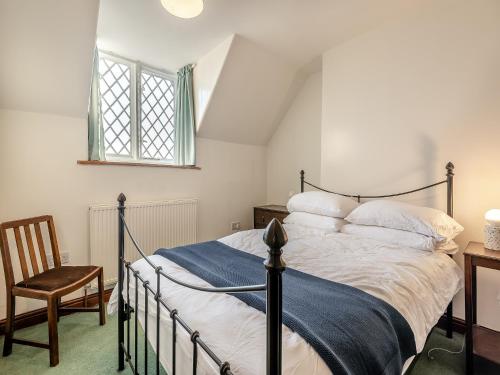 a bedroom with a bed and a chair and a window at Badger Cottage in Cressbrook