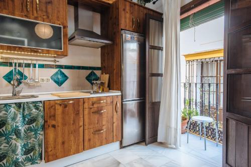 una cocina con armarios de madera y una gran ventana en Increible Casa Independiente en Santa Cruz, Parking Optional, en Sevilla