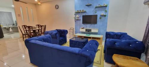 a living room with blue couches and a tv at Flora Homestay Jenjarom, Banting,Telok Panglima Garang in Jenjarum