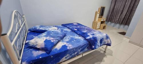 a bed with a blue comforter in a room at Flora Homestay Jenjarom, Banting,Telok Panglima Garang in Jenjarum
