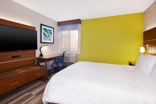 a hotel room with a bed and a flat screen tv at Holiday Inn Express Fairfax-Arlington Boulevard by IHG in Fairfax