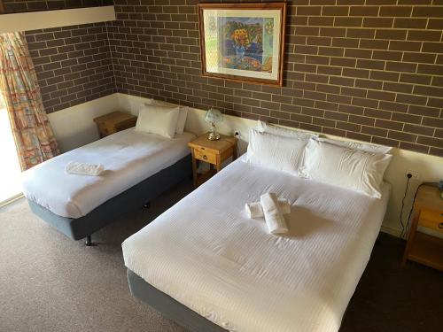 2 camas en una habitación con una pared de ladrillo en Barmera Hotel Motel, en Barmera