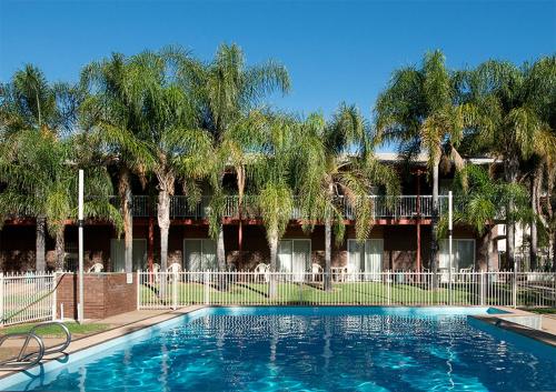 a swimming pool in front of a building with palm trees at Barmera Hotel Motel in Barmera
