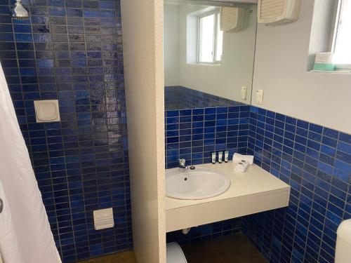 Baño de azulejos azules con lavabo y espejo en Barmera Hotel Motel, en Barmera