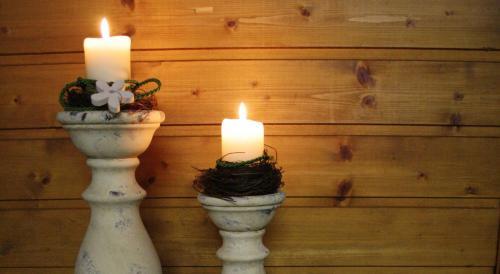 two candles in vases sitting against a wooden wall at Apartments HAUS SCHÖN - Preise inclusive Pitztal Sommer Card in Jerzens
