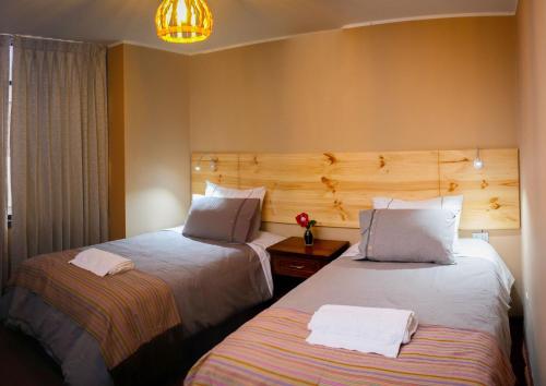Habitación de hotel con 2 camas y lámpara de araña. en Colibrí Inn en Chivay