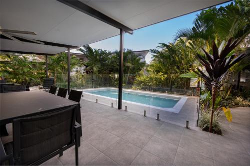um pátio com uma mesa e uma piscina em Tropicana Villas at Clifton Beach em Clifton Beach