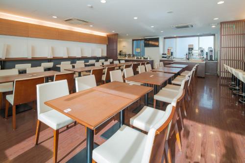 comedor con mesas de madera y sillas blancas en Meitetsu Inn Nagoya Ekimae en Nagoya