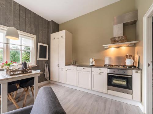 uma cozinha com armários brancos, uma mesa e um fogão em Quaint Summer Holiday Home in Egmond Binnen em Egmond-Binnen