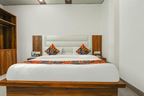 a bedroom with a large white bed with orange pillows at FabExpress Sagar Residency in Mussoorie