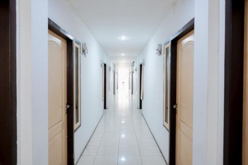 a hallway with white walls and white tile floors at RedDoorz near Tugu Pers Jambi in Jambi