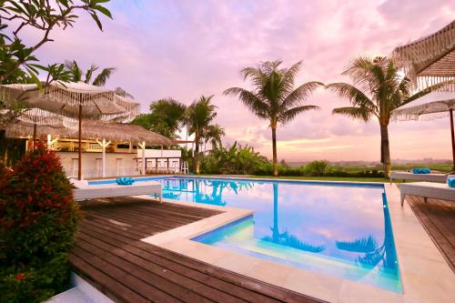 a pool at a resort with palm trees at 37 Sunset Village Bali in Canggu