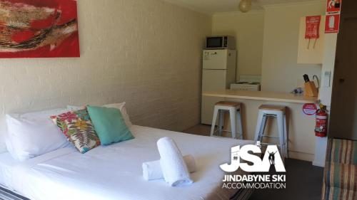 1 dormitorio con 1 cama blanca y 2 taburetes en Ellswood 1, en Jindabyne
