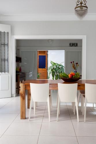 a dining room with a wooden table and white chairs at Pousada Casa da Vitória in Salvador