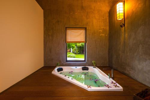 a jacuzzi tub in a room with a window at Chaarya Resort & Spa in Tissamaharama