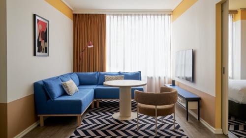 um quarto de hotel com um sofá azul e uma mesa em Laneways by Ovolo em Melbourne