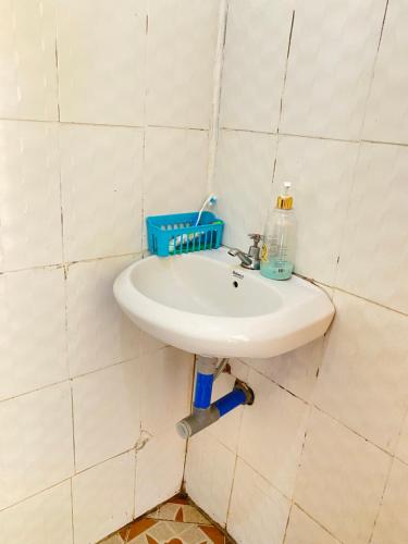 un fregadero blanco en una pared de azulejos con una botella. en Cozy studio apartment en Arusha