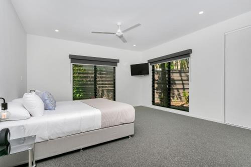 1 dormitorio blanco con 1 cama y ventilador de techo en Tiino Villa with Heated Pool Clifton Beach en Clifton Beach