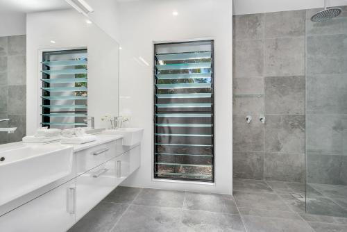 y baño con ducha, lavabo y espejo. en Tiino Villa with Heated Pool Clifton Beach en Clifton Beach