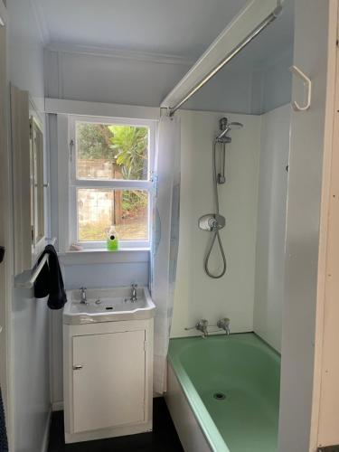 y baño con bañera verde, lavabo y ducha. en Toad Hall, en Baylys Beach