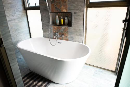 baño con bañera blanca y ventana en EMC Fully Furnished &Serviced Apartments 4 bedroom with a private Pool, Wifi ,Aircons & Dstv, en Lusaka