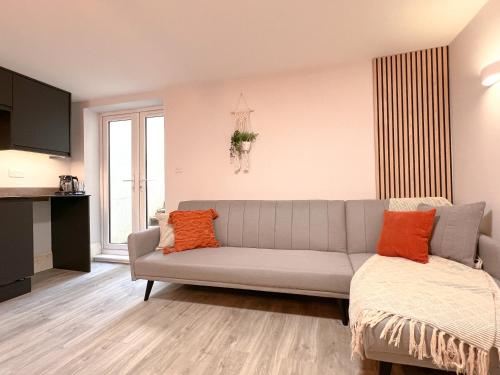 - un salon avec un canapé gris et des oreillers orange dans l'établissement The Bohemian Basement, à Kent