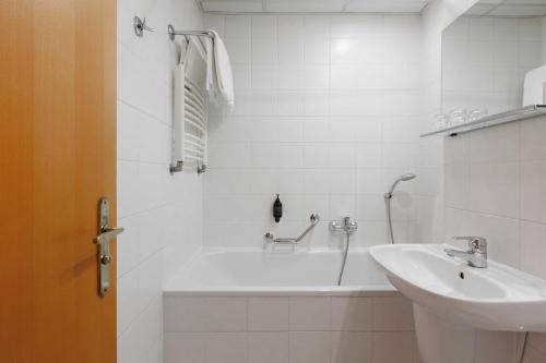a white bathroom with a tub and a sink at OREA Hotel Voro Brno in Brno