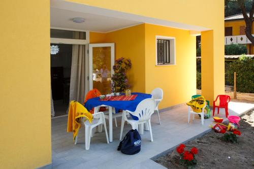 a patio with a table and chairs and a yellow house at Principesse in Rosolina Mare