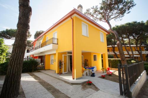 a yellow house with a tree and a fence at Principesse in Rosolina Mare