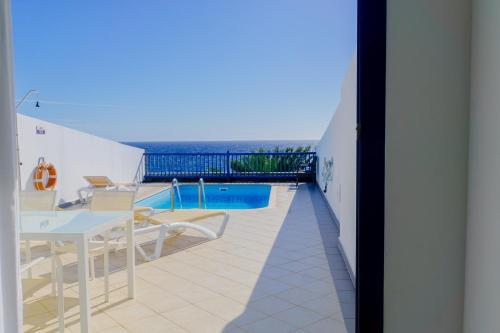 uma varanda com uma mesa e cadeiras e uma piscina em La Casa Azul em Puerto Calero