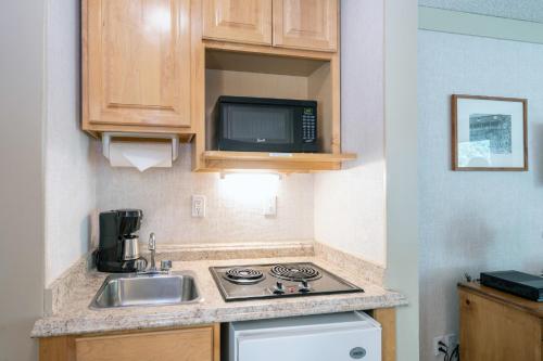 a small kitchen with a sink and a microwave at Mountainside Inn 411 by Alpine Lodging Telluride in Telluride