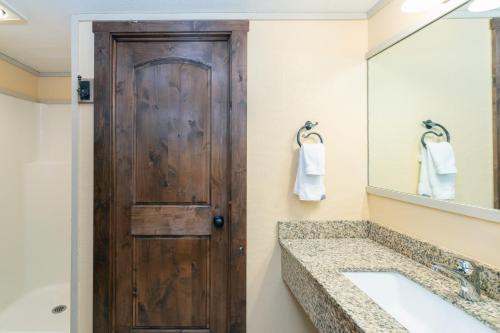 a bathroom with a wooden door and a sink at Mountainside Inn 411 Hotel Room in Telluride