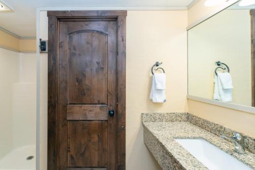 a bathroom with a wooden door and a sink at Mountainside Inn 411 by Alpine Lodging Telluride in Telluride