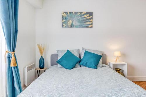 a bedroom with a bed with blue pillows at STUDIO SPA, CENTRE VILLE DE SANNOIS, PARKING PRIVE in Sannois