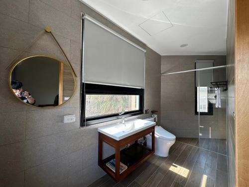a bathroom with a sink and a mirror and a toilet at 九屏文旅 JP guesthouse in Xiyu