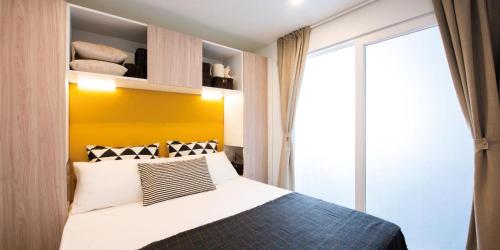 1 dormitorio con 1 cama con pared amarilla en Camping villaggio L'Ultima spiaggia, en Bari Sardo