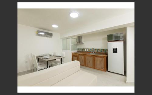 Il comprend une cuisine équipée d'une table et d'un réfrigérateur blanc. dans l'établissement Room in Apartment - Apartment Rodolfo Historic Center, à Mazatlán