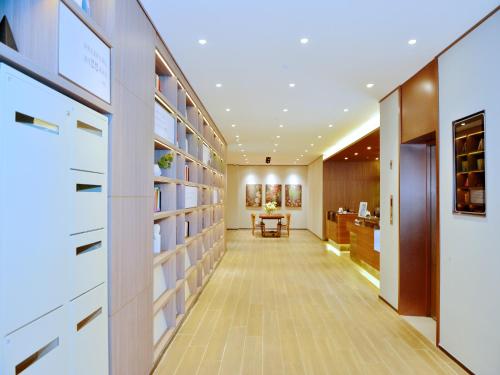 a long hallway with white shelves and a table in a room at Hanting Shenzhen Nanshan Metro Station in Shenzhen