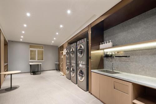 a laundry room with four washer and dryer machines at Hanting Hotel Chongqing Niujiaotuo Railway Station in Chongqing