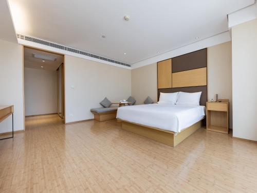 a bedroom with a large white bed and wooden floors at JI Hotel Nanjing Hongqiao Zhongshan North Road in Nanjing