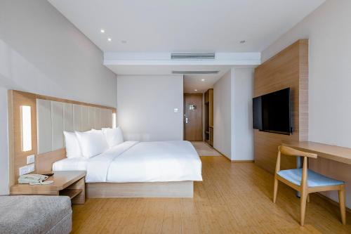 a hotel room with a large bed and a television at JI Hotel Shanghai Songjiang Sports Center in Songjiang