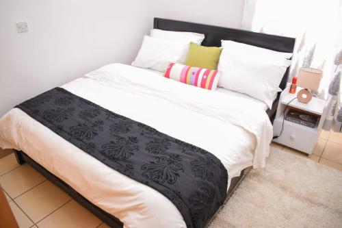 a large bed with black and white sheets and pillows at Luxe Homes in Syokimau